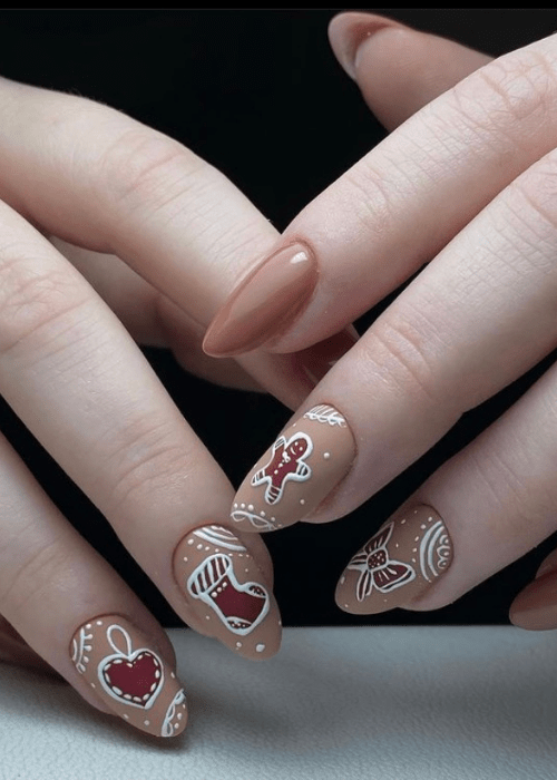 Tan Christmas nail design with little red designs of a gingerbread man and a Christmas stocking