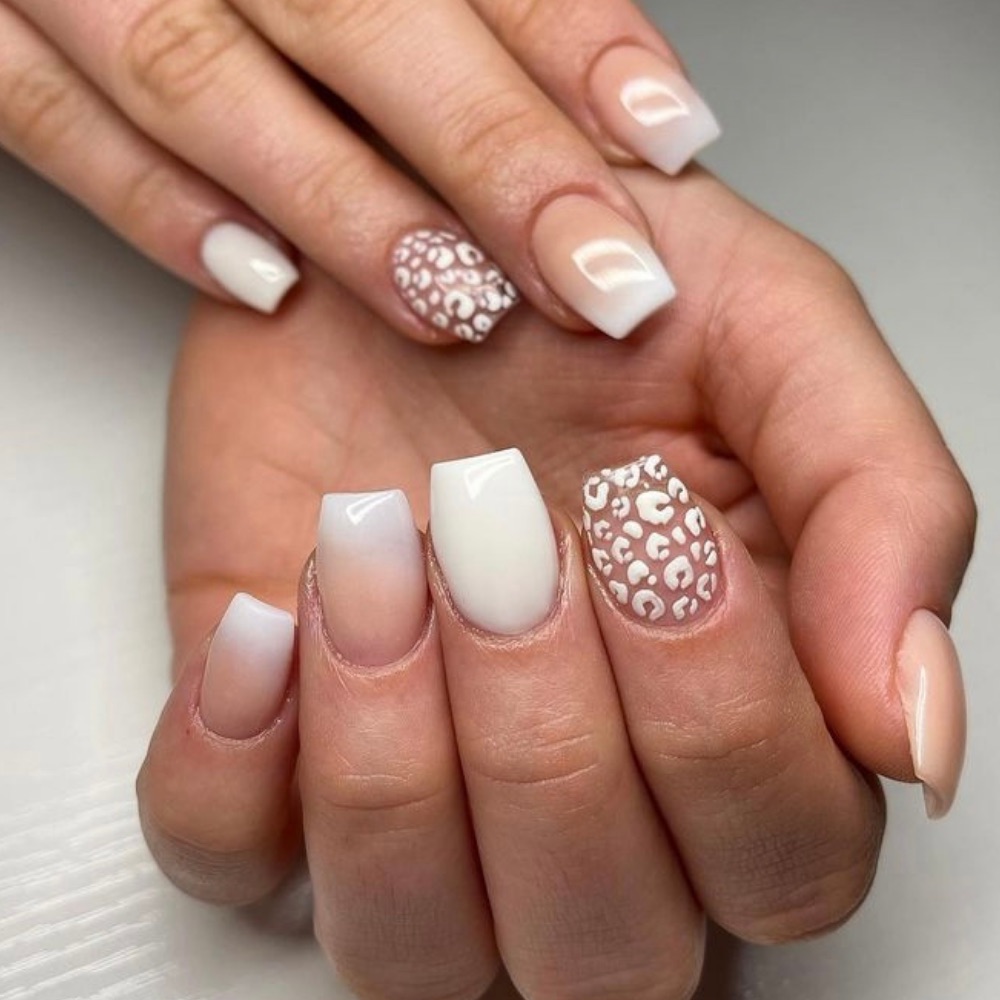 A white set of nails with a leopard print design and a ombre