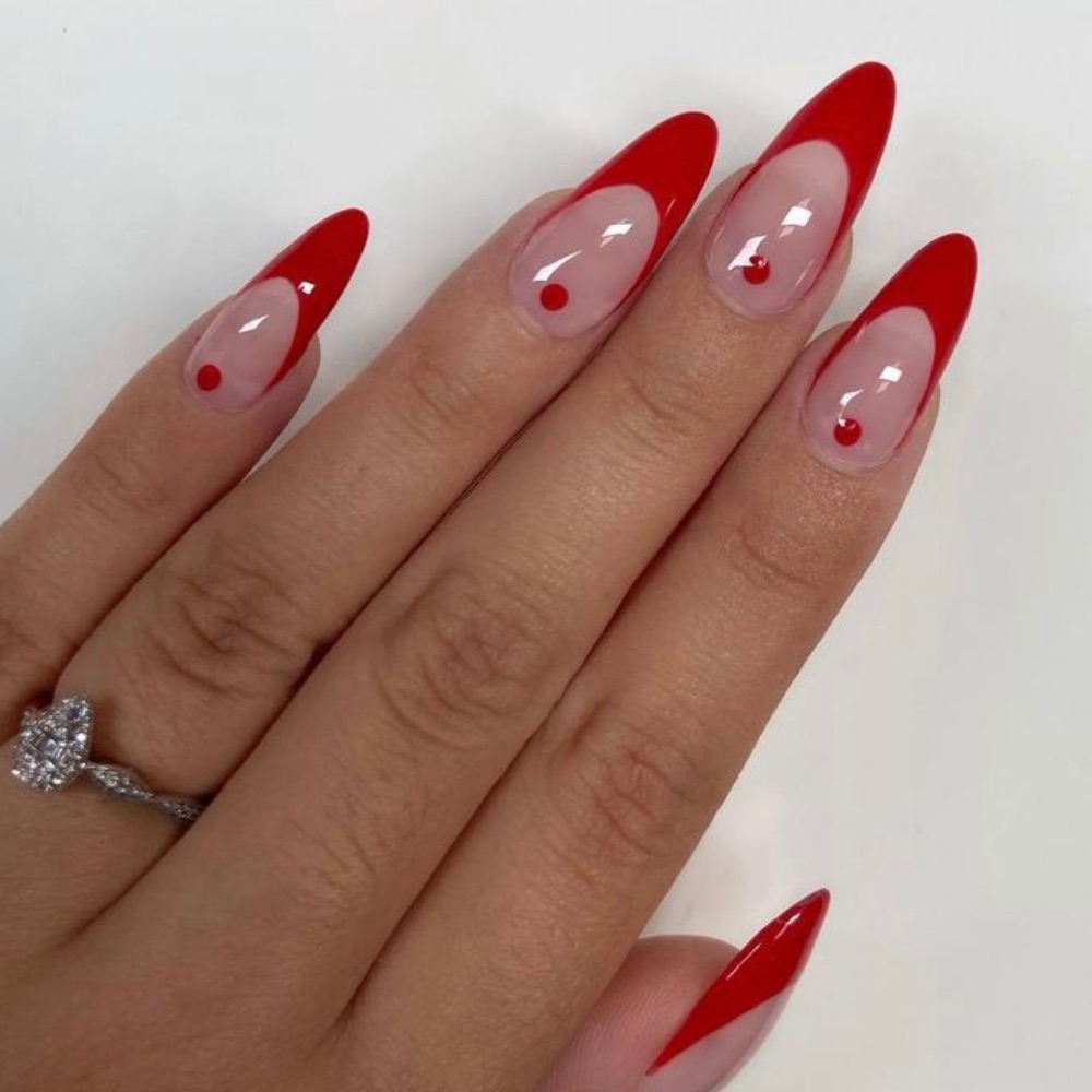 A simple red nail design with a French tip and a dot at the bottom of the nail