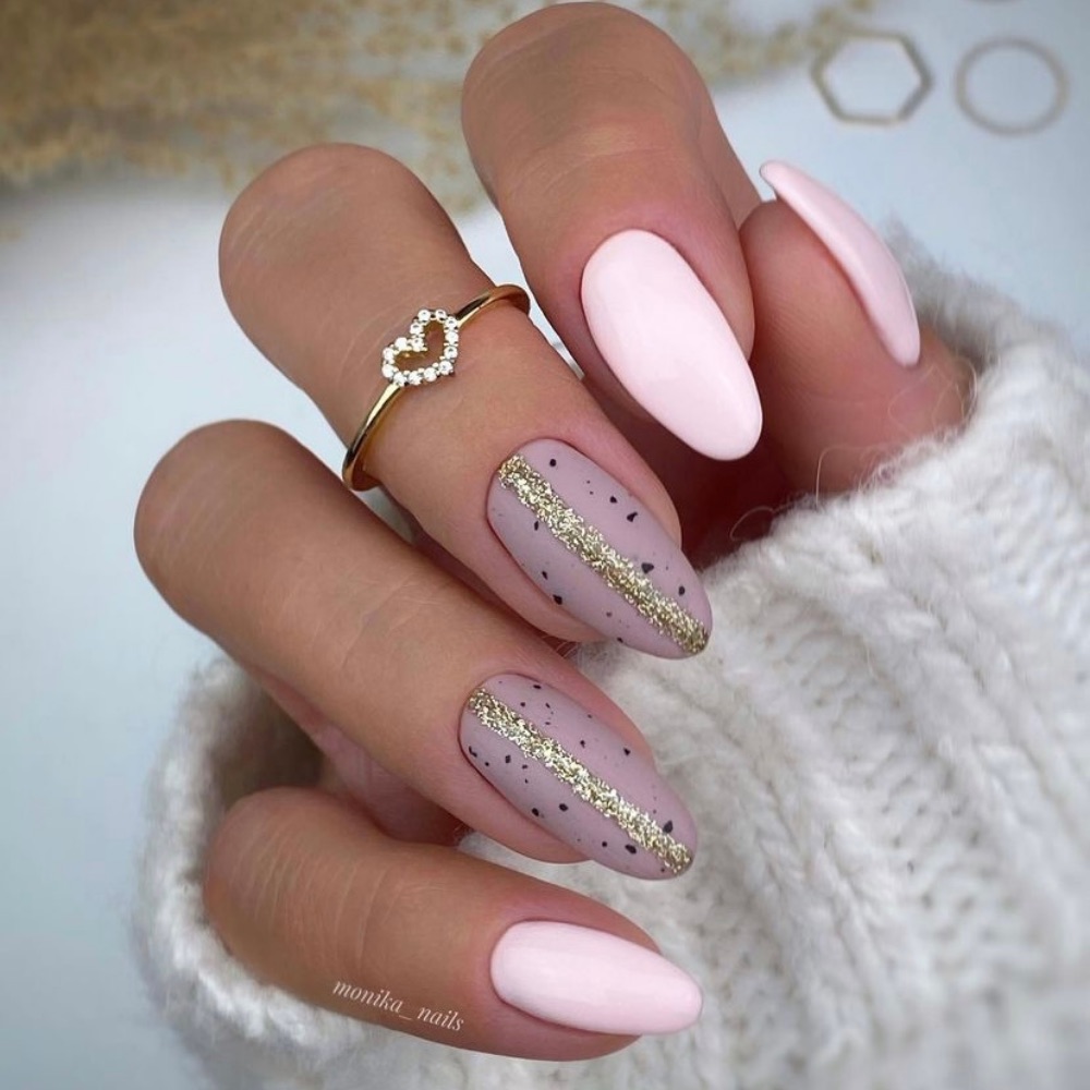 Short almond nails with two pink nails and and two light purple nails with a design