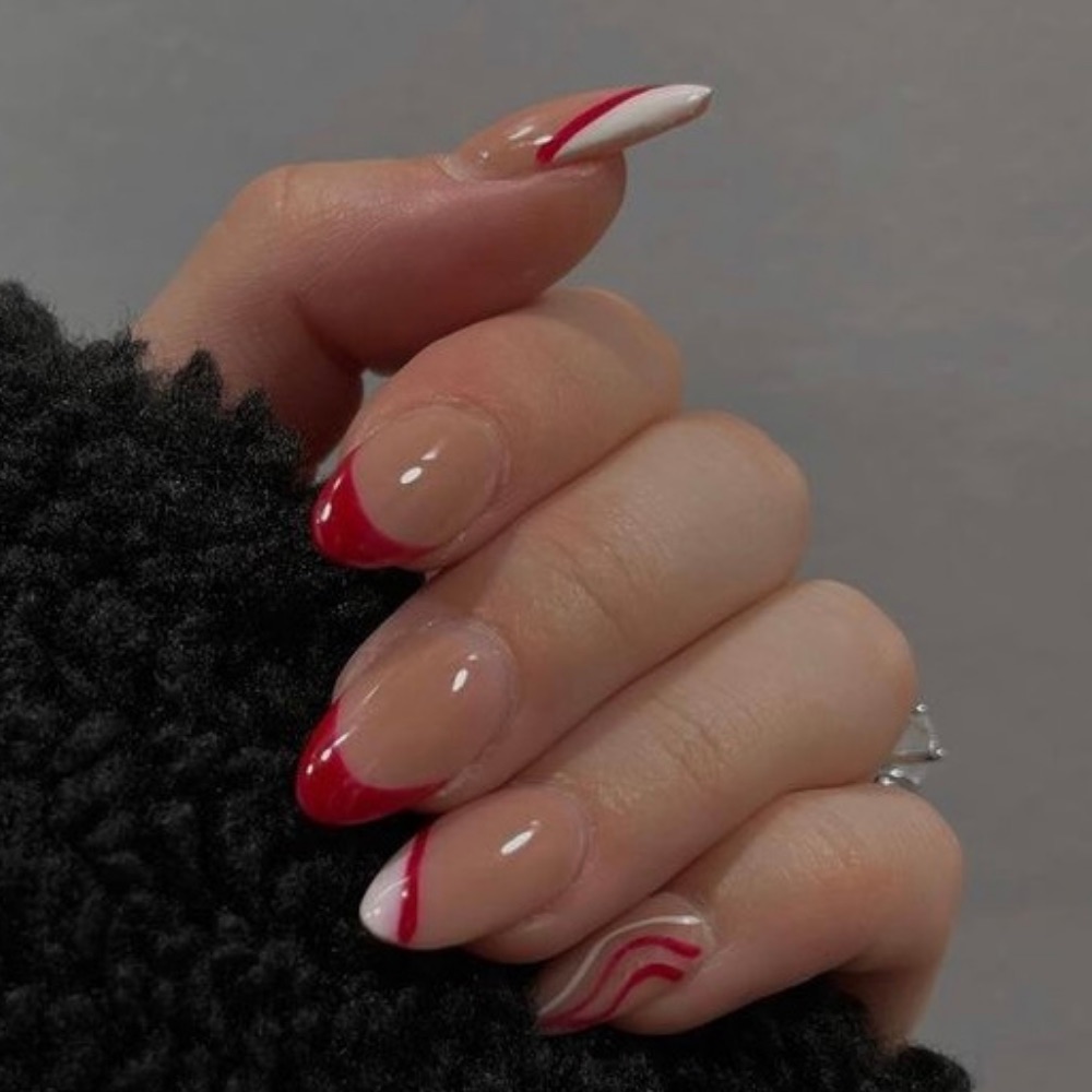 A red and white nail design with French tips and swirls