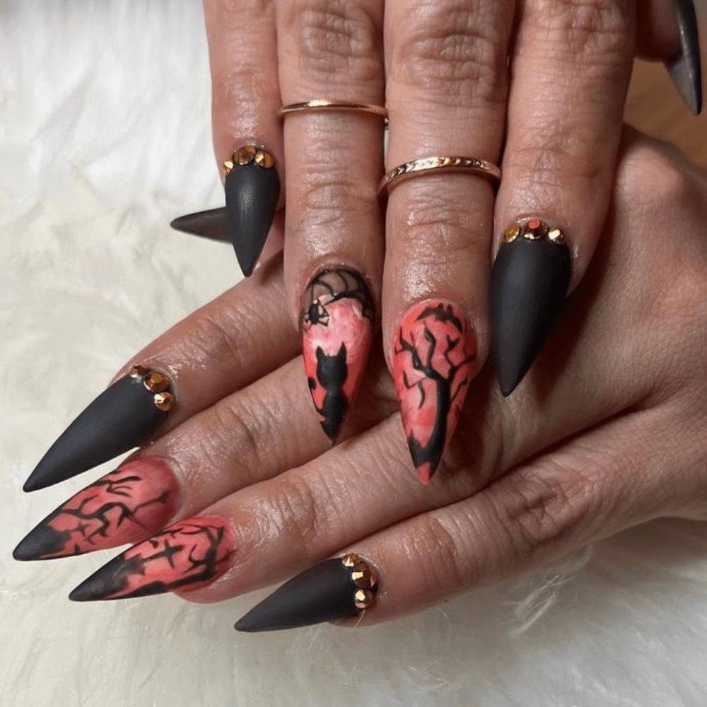 Red and black nail design with trees and a black cat on stilleto nails