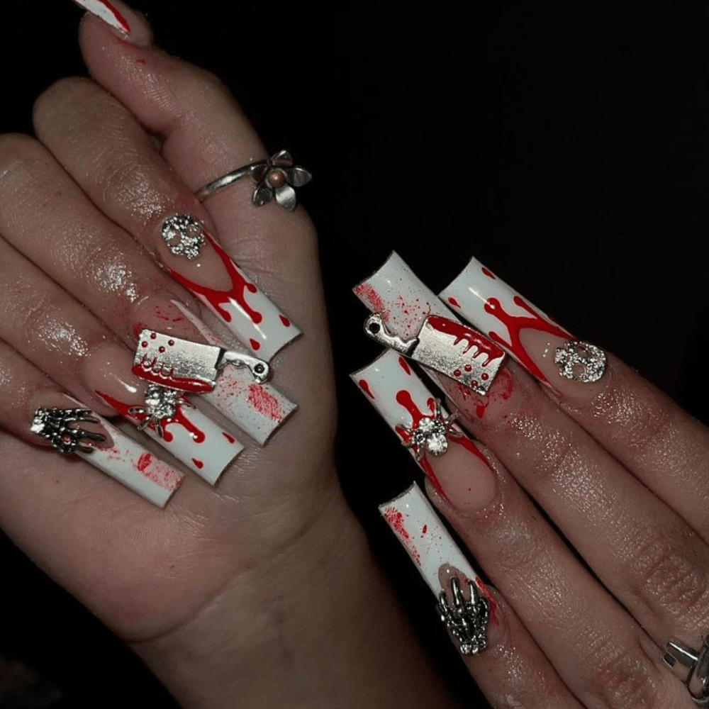 White French tip nails with a dripping blood design and gems